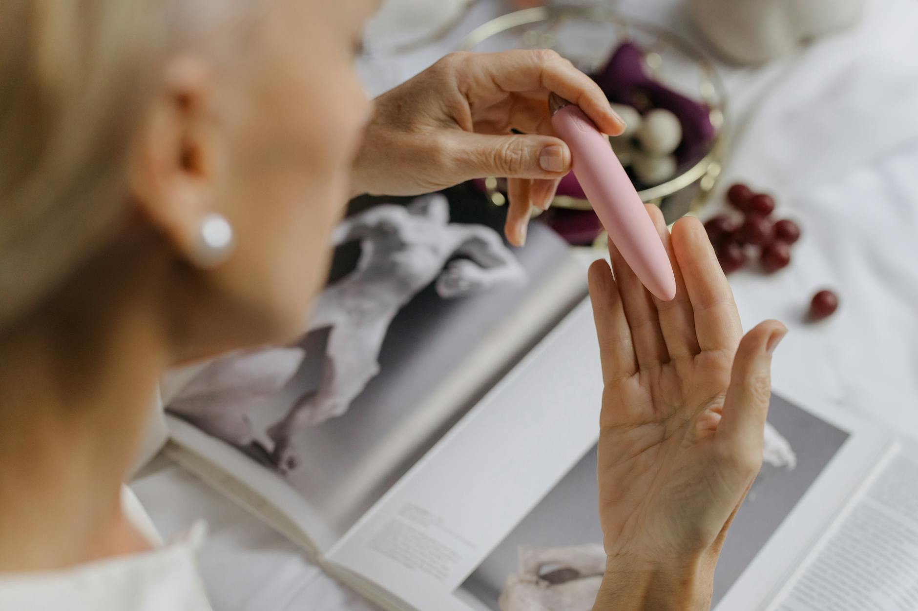 Close-up of hands exploring texture and sensation with a pink vibrator, emphasizing tactile intimacy.