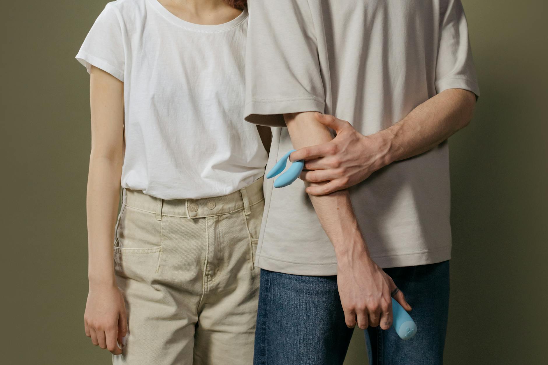 Woman holding blue and pink silicone vibrators, thoughtfully considering her options